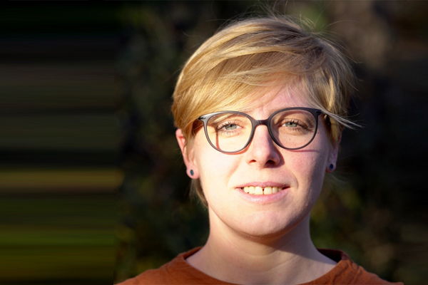 ein Portrait einer blonden Frau mit kurzen Haaren und Brille