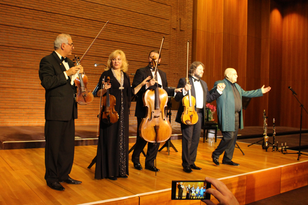 eine Frau und vier Männer mit Instrumenten in den Händen, die sich auf einer Bühne verbeugen
