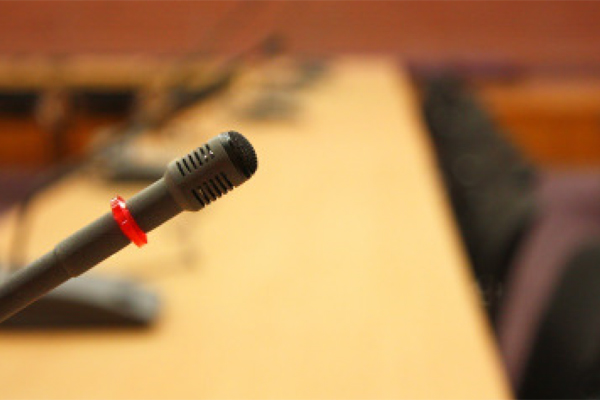 langer Konferenztisch, im Vordergrund ein Mikrofon