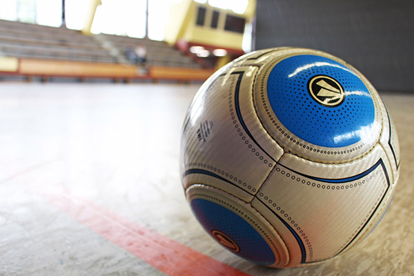 einen Fußball auf dem Boden einer Sporthalle.