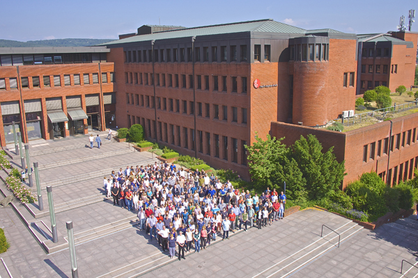 eine große Gruppe Menschen vor einem großen Gebäude, aufgenommen aus der Luft