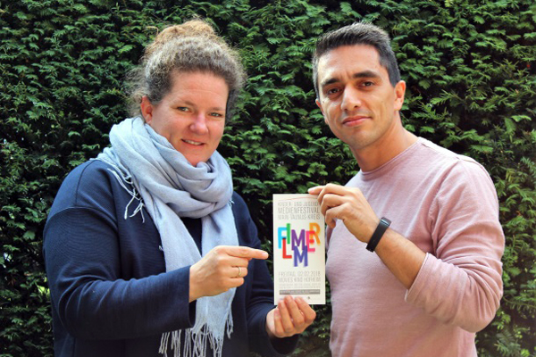 eine Frau und ein Mann halten einen Flyer mit der Aufschrift Flimmer in die Kamera