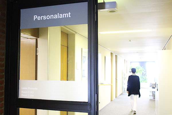 den Flur des Personalamts, den eine Frau entlanggeht.