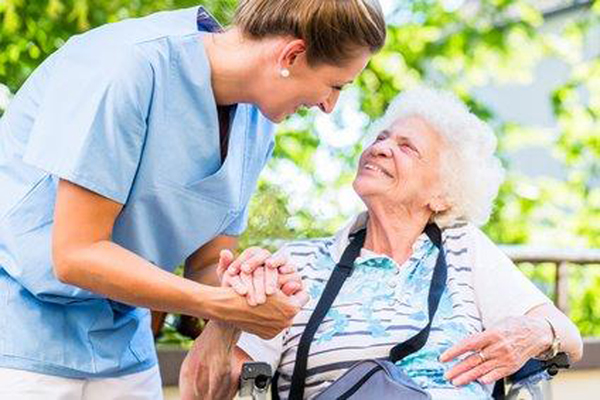 eine Pflegerin hält die Hand einer Seniorin
