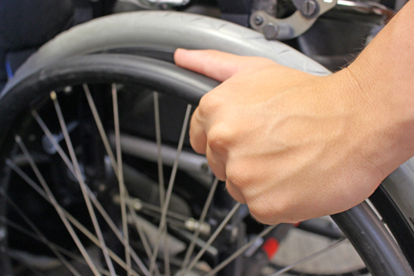 eine Hand an einem Rollstuhlrad