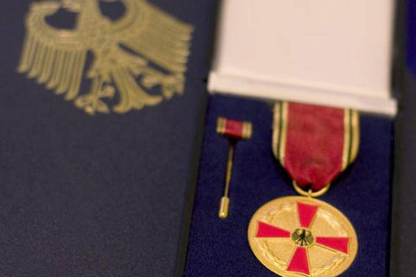einen Orden in einem Schmuckkasten auf einer Mappe mit dem deutschen Wappen