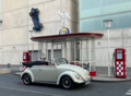 Cremefarbenes Cabrio vor einer alten Tankstelle, mit einem Automodell, das an einer WAnd hängt | Copyright: Teilnehmer Cremefarbenes Cabrio vor einer alten Tankstelle, mit einem Automodell, das an einer WAnd hängt