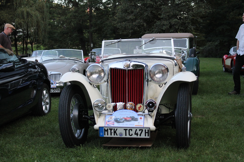 Weißes Cabriolet mit rotem Kühlergrill parkt mit anderen Autos auf einer Wiesen | Copyright: Teilnehmer Weißes Cabriolet mit rotem Kühlergrill parkt mit anderen Autos auf einer Wiesen