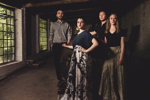 zwei Männer und Frauen stehen in Abendgarderobe in einem alten Gebäude
