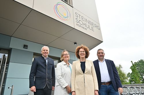 zwei Männer und zwei Frauen vor dem Logo der Steinbergschule

