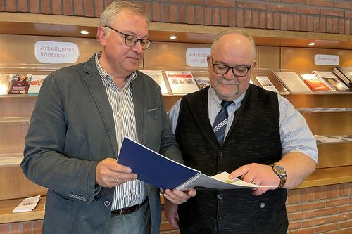 zwei Männer betrachten ein Berichtsheft
