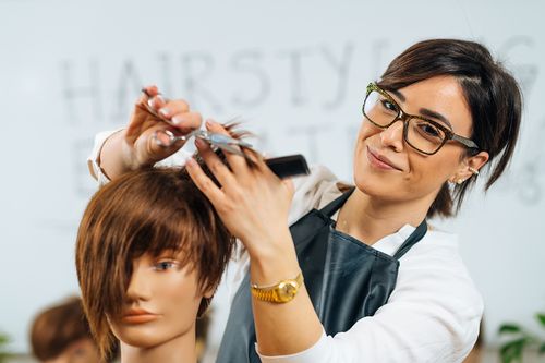 eine Friseurin kämmt einen Puppenkopf
