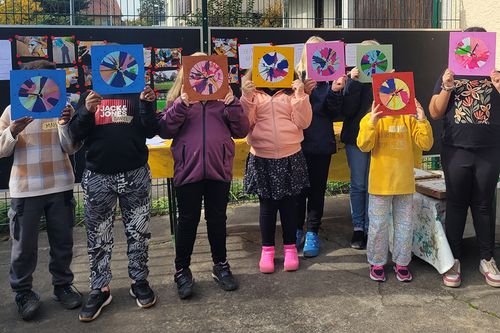Kinder halten gemalte Bilder zum Thema Zeitgefühl hoch.
