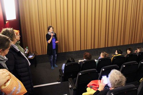 Ein Symbolfoto der letztjährigen Filmvorführung: Es zeigt die externe Gleichstellungsbeauftragte des Main-Taunus-Kreises Martina Weyand-Ong im Kinosaal bei der Eröffnungsrede
