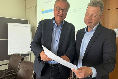 Zwei Personen sehen sich einen Bericht an.
