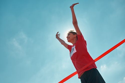 Eine Person läuft durch das Ziel, das mit einem roten Band gekennzeichnet ist
