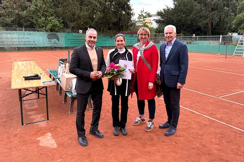 Ein Gruppenfoto von vier Personen auf einem Tennisplatz

