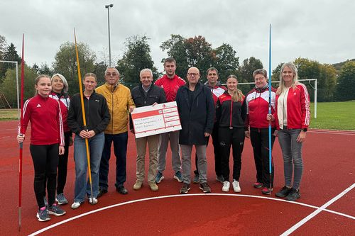 Eine Gruppe von elf Personen auf einem Sportplatz.
