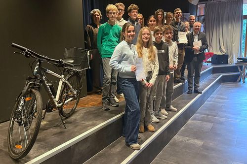 Gruppenfoto mit mehreren Kindern und vier Erwachsenen. neben ihnen steht ein Fahrrad
