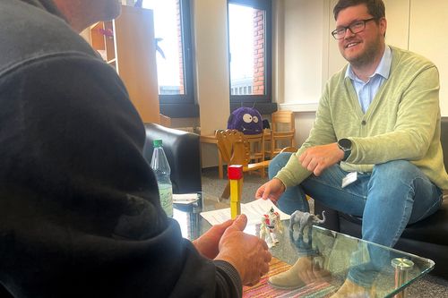 Zwei Männer unterhalten sich an einem Tisch sitzend
