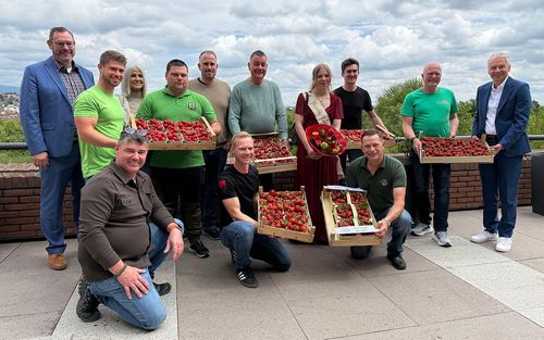 Ein Gruppenfoto mit mehreren Menschen, die Erdbeerschalen in den Händen halten
