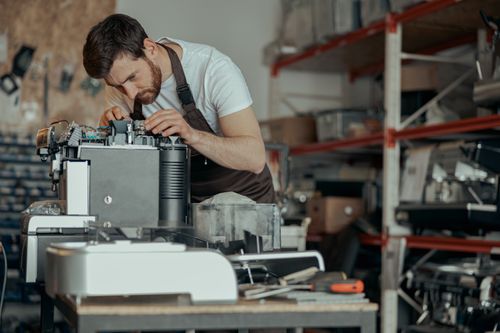 Ein Mann repariert eine Kaffeemaschine
