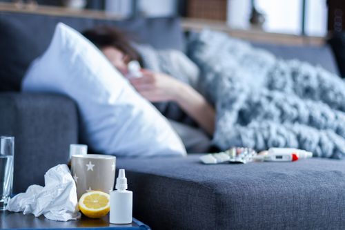 Eine Person liegt krank auf dem Sofa unter einer Decke