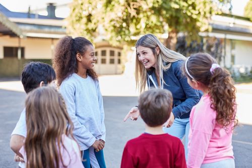 Kinder und Betreuerin auf Schulhof