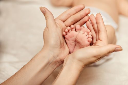Eine Erwachsene Hand hält zwei Babyfüße