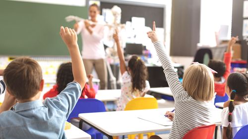 Kinder im Klassenraum, die sich engagiert melden